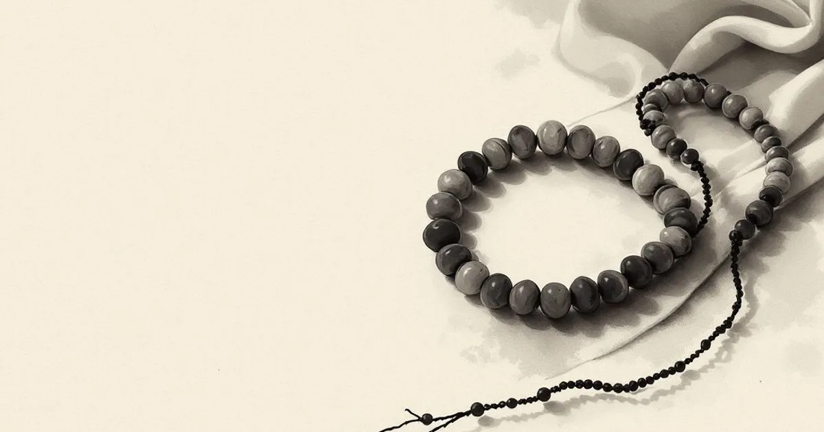 Sumi-e ink-wash illustration: a loop of prayer beads coiled on a plain cloth.